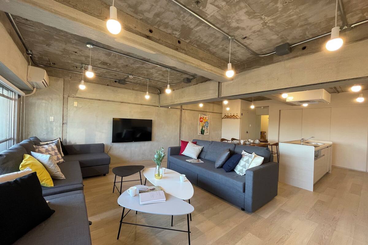 A modern living space with a grey sofa set, a white coffee table, and a flat-screen TV mounted on the wall.