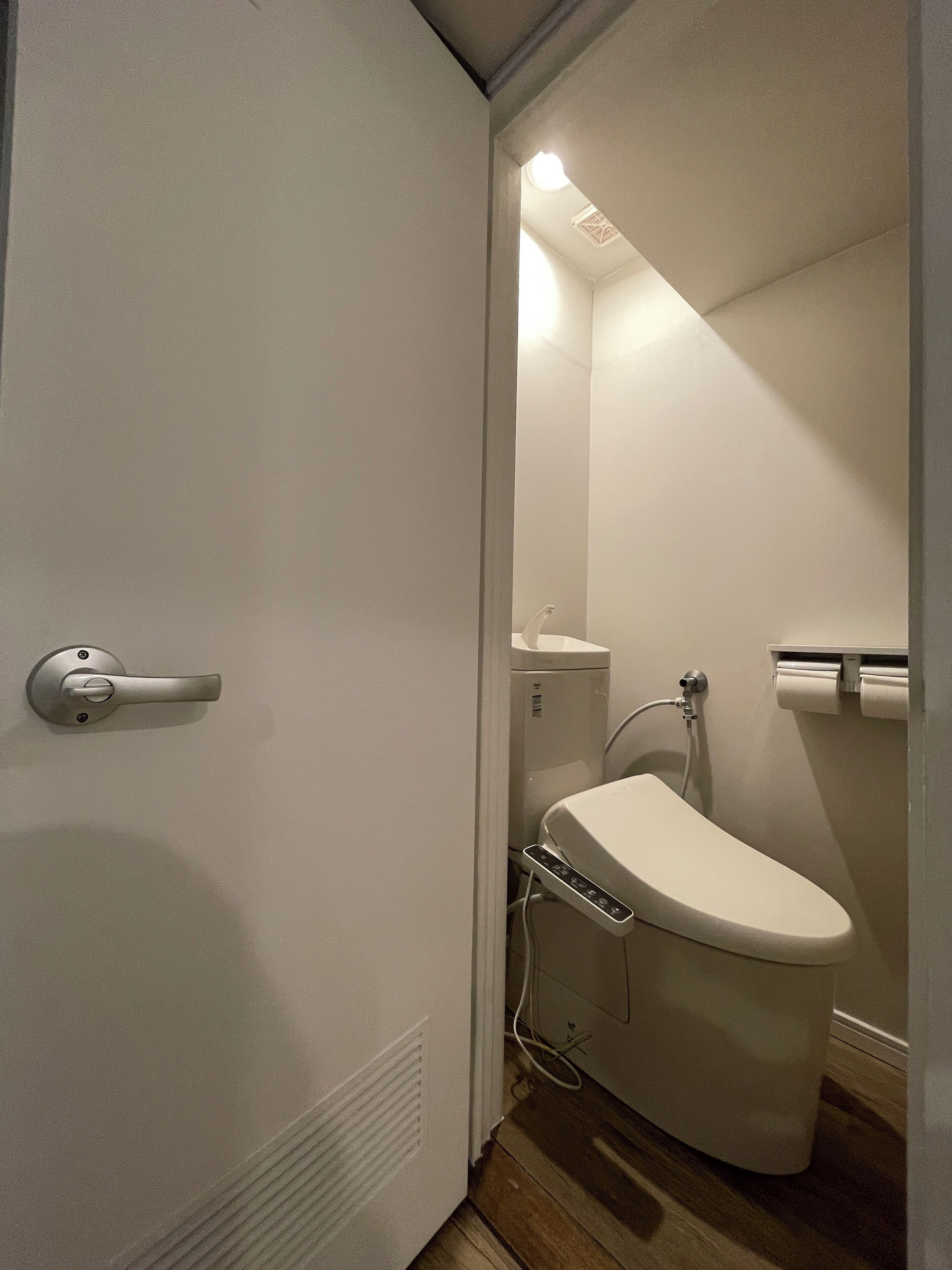 A small, compact bathroom with a toilet, a sink, and a mirror.