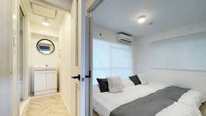 A bedroom with a bed, a bedside table, a mirror, and an air conditioning unit. -  Dai3Himawari 604 (Hiroshima)