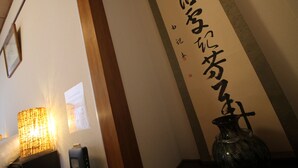 Una habitación con una caligrafía japonesa tradicional en la pared, una lámpara y un florero.