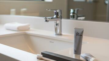 A modern bathroom with a white sink, a mirror, and a toothbrush holder.