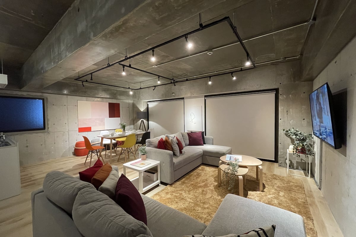 Una sala moderna con un sofá modular, un comedor y un televisor de pantalla plana montado en la pared.