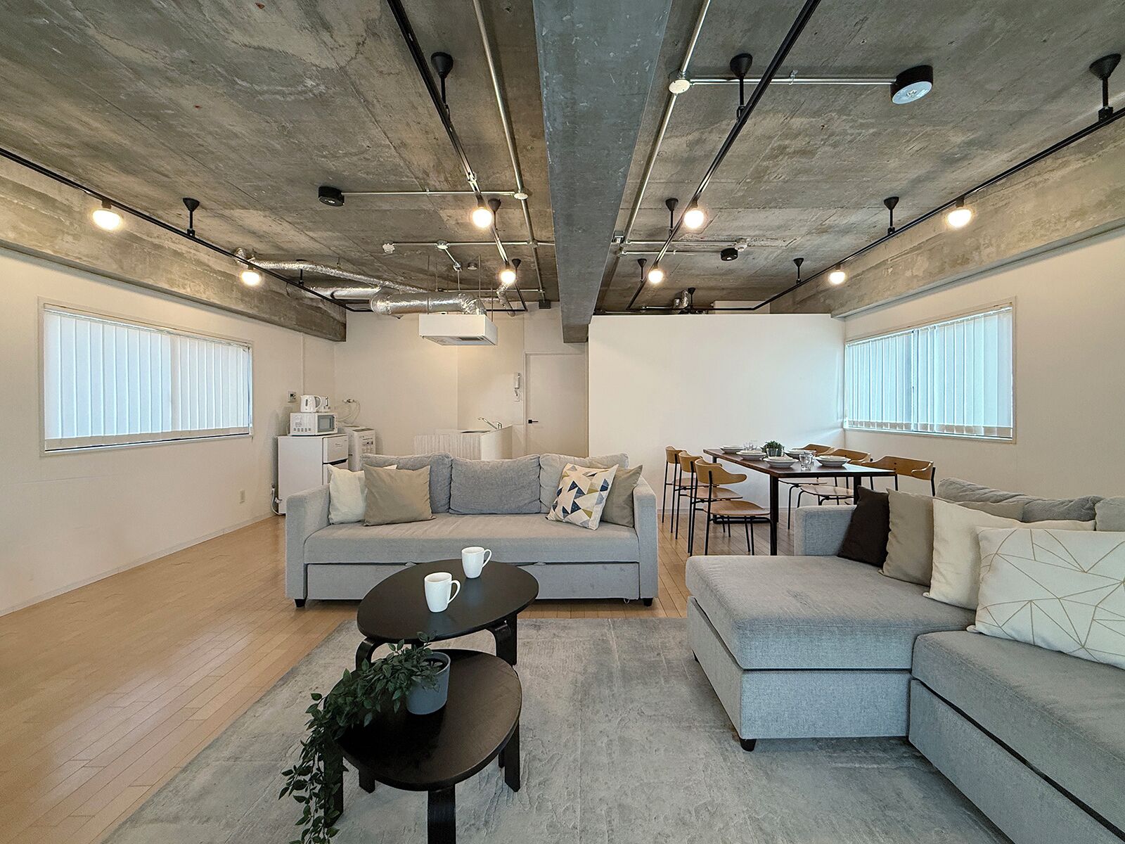 Een moderne woonkamer met een grijze bank, een salontafel en een eethoek met stoelen en een tafel.