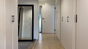 A hallway with wooden flooring, white walls, and doors leading to rooms. - M's Lea Building (Hiroshima)