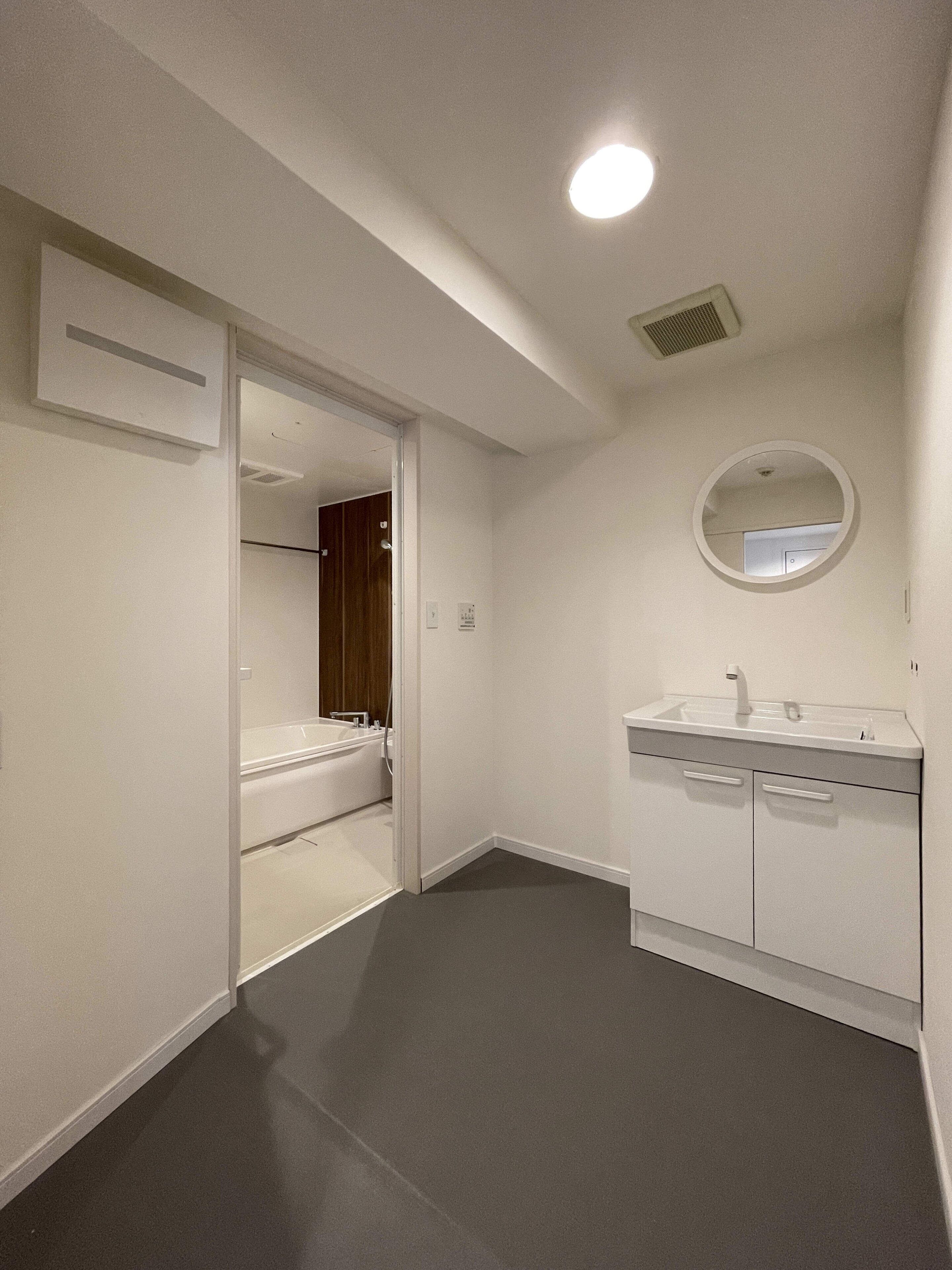 Un baño moderno con lavamanos blanco, espejo y cabina de ducha.