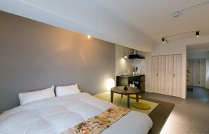Una habitación de hotel moderna con una cama grande, una mesa redonda pequeña, un escritorio con silla y un armario.