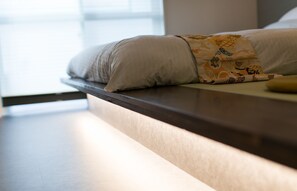 Una cama con cabecera, almohadas y una colcha estampada.