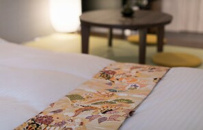 Una cama con una colcha estampada con motivos florales y una manta doblada con cuidado.