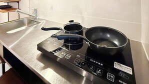 Eine moderne Küche mit einer Edelstahlarbeitsplatte, einem eingebauten Herd, einer Dunstabzugshaube und einem an der Wand montierten Handtuchhalter.