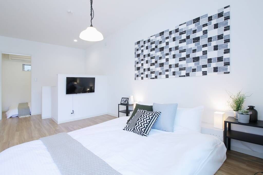 A modern bedroom with a large bed, a wall-mounted TV, and a unique patterned wall art.