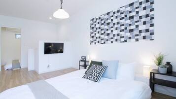 A modern bedroom with a large bed, a wall-mounted TV, and a unique patterned wall art.
