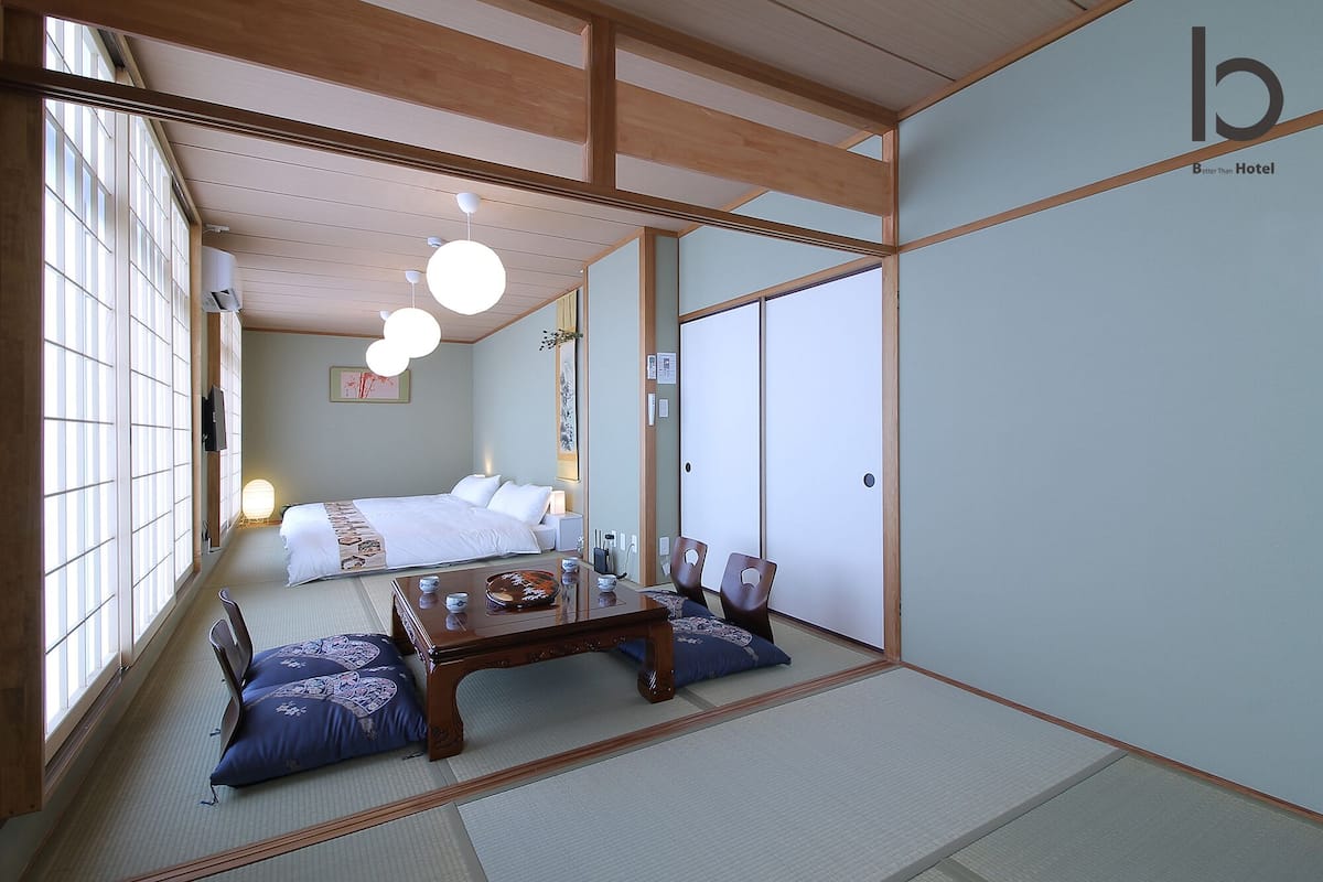 A traditional Japanese-style room with tatami flooring, a low wooden bed, and a small table with a tea set.
