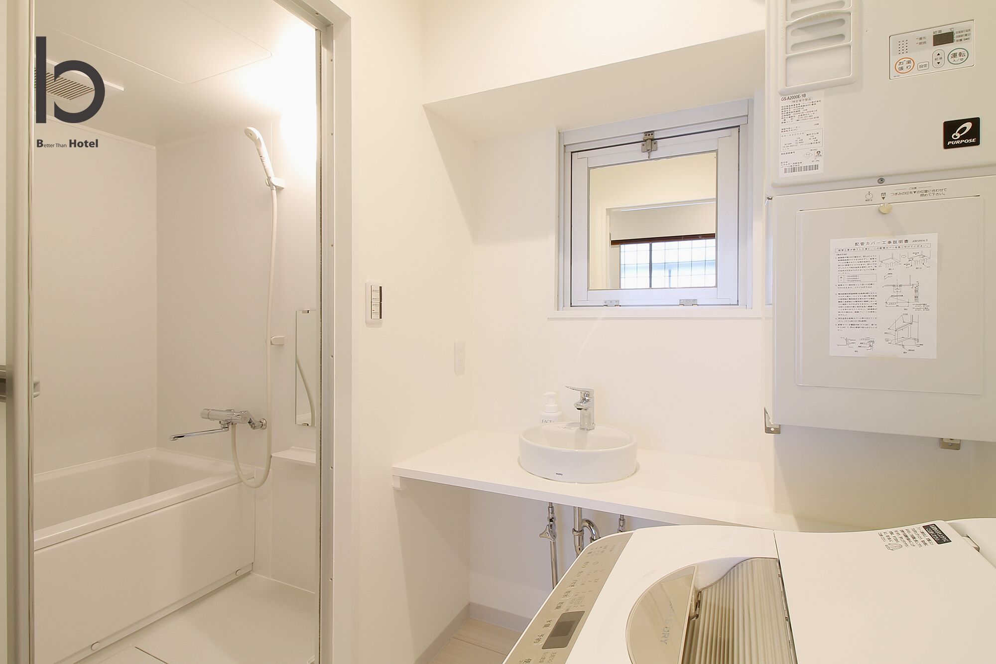 A hotel bathroom with a bathtub, a sink, and a window.