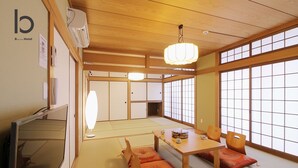 A traditional Japanese room with tatami flooring, a low table with cushions, and sliding doors. - Hanagin Building (Hiroshima)