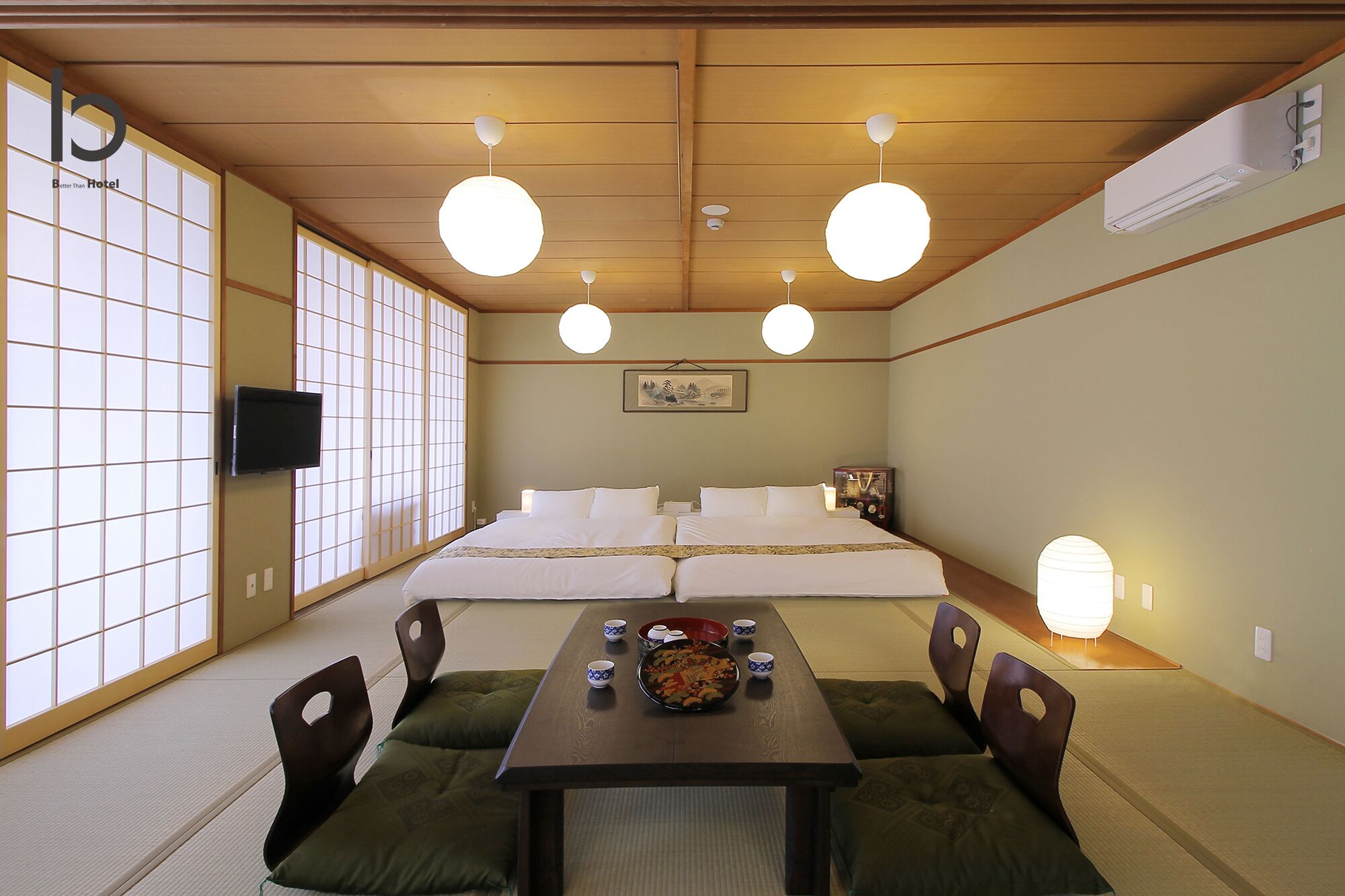 A traditional Japanese-style room with tatami flooring, a low table with cushions, a bed with white bedding, and shoji screens on the windows.