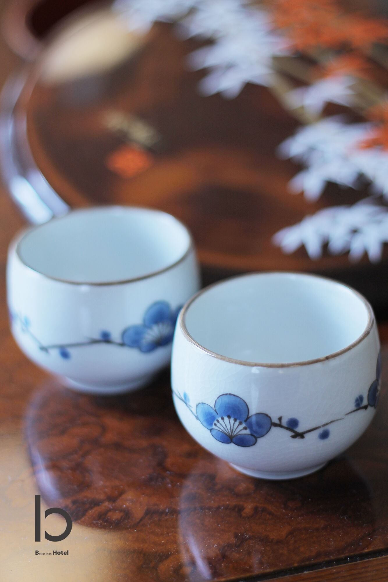 Two small cups with blue floral designs on a reflective surface.