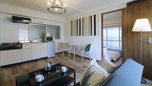 Ein modernes Hotelzimmer mit Küchenzeile, Essbereich, einer Couch und einer Lampe.