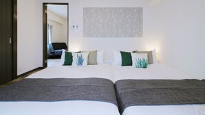 Ein Hotelzimmer mit zwei Betten, einem großen Spiegel, einer Wanddekoration mit Muster und einer Tür zu einem weiteren Raum.
