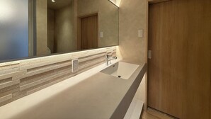 A modern bathroom with a large mirror, a white sink, and wooden doors. - Ishiki Building (Hiroshima)