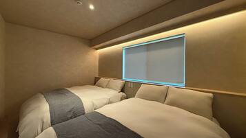 A hotel room with two beds, a large window with a blue frame, and a ceiling light.