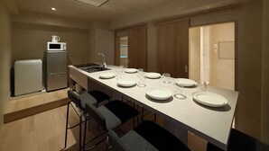 A modern kitchen with a central island, bar stools, a microwave, and a refrigerator. - Ishiki Building (Hiroshima)