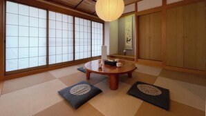 A traditional Japanese room with tatami flooring, a low wooden table, and a hanging paper lantern. - Mbuilding (Hiroshima)