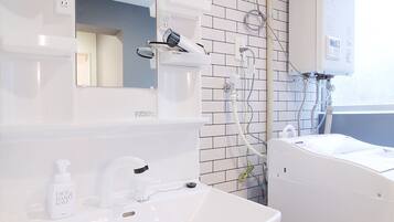 A modern bathroom with a white sink, mirror, and a built-in shower.