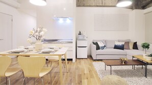 A modern living space with a dining area, a kitchenette, and a seating area with a sofa and coffee table.