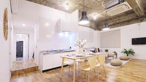 A modern kitchen with white cabinets, a wooden dining table, and a seating area with chairs and a sofa.