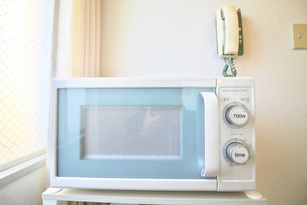 A white microwave oven with a control panel, including a 700W setting and a timer.