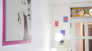Una habitación con una obra de arte grande enmarcadas en la pared, una puerta blanca con vidrieras y un teléfono instalado en la pared.