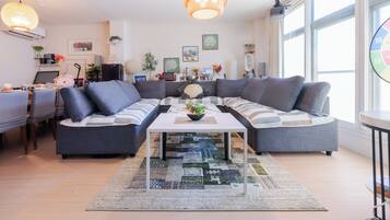 Una sala moderna con un sofá modular, una mesa de centro y un comedor con sillas.