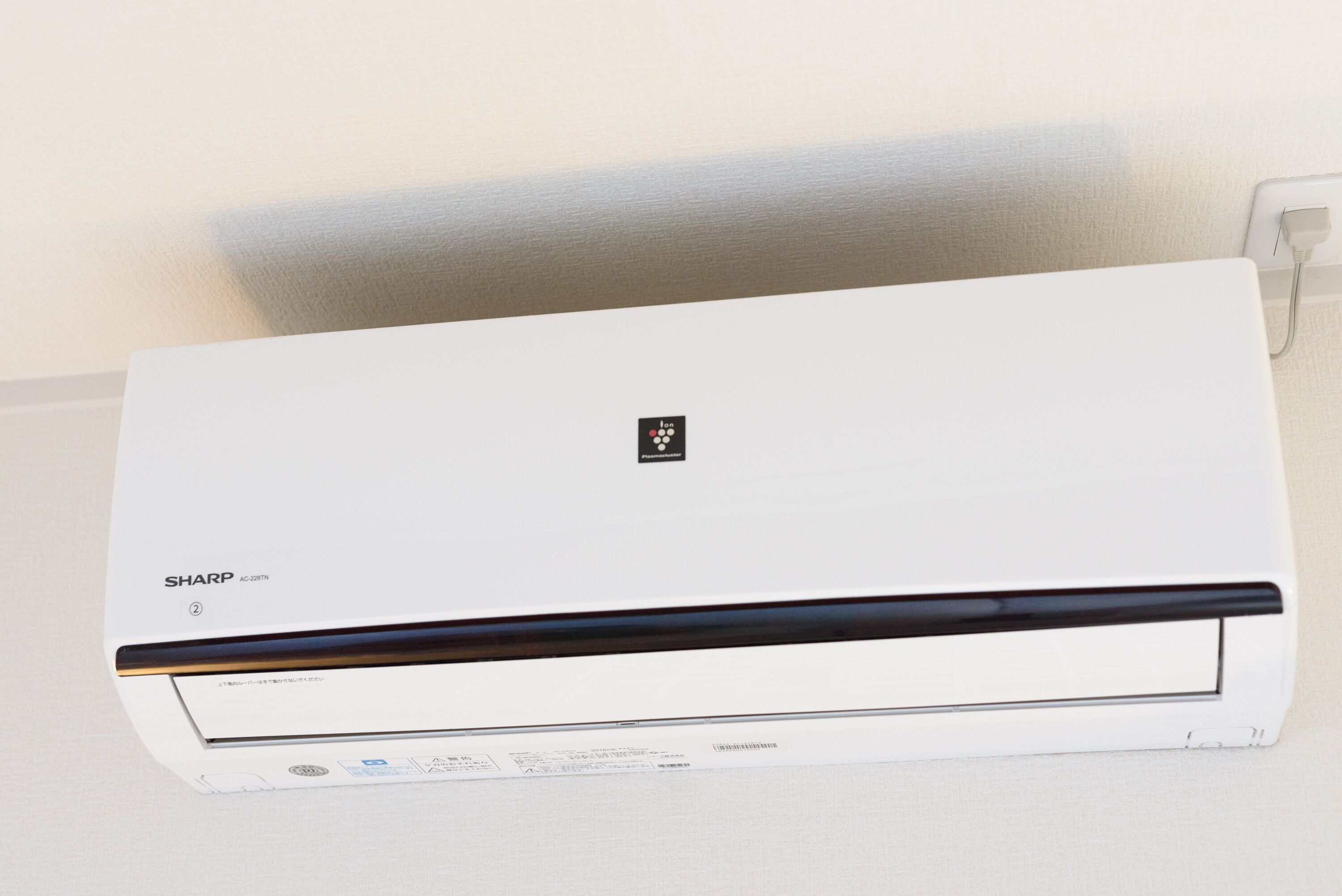 Eine weiße Klimaanlage mit dem Markenname 'SHARP' und der Modellnummer 'AC-228TN' auf der Vorderseite.