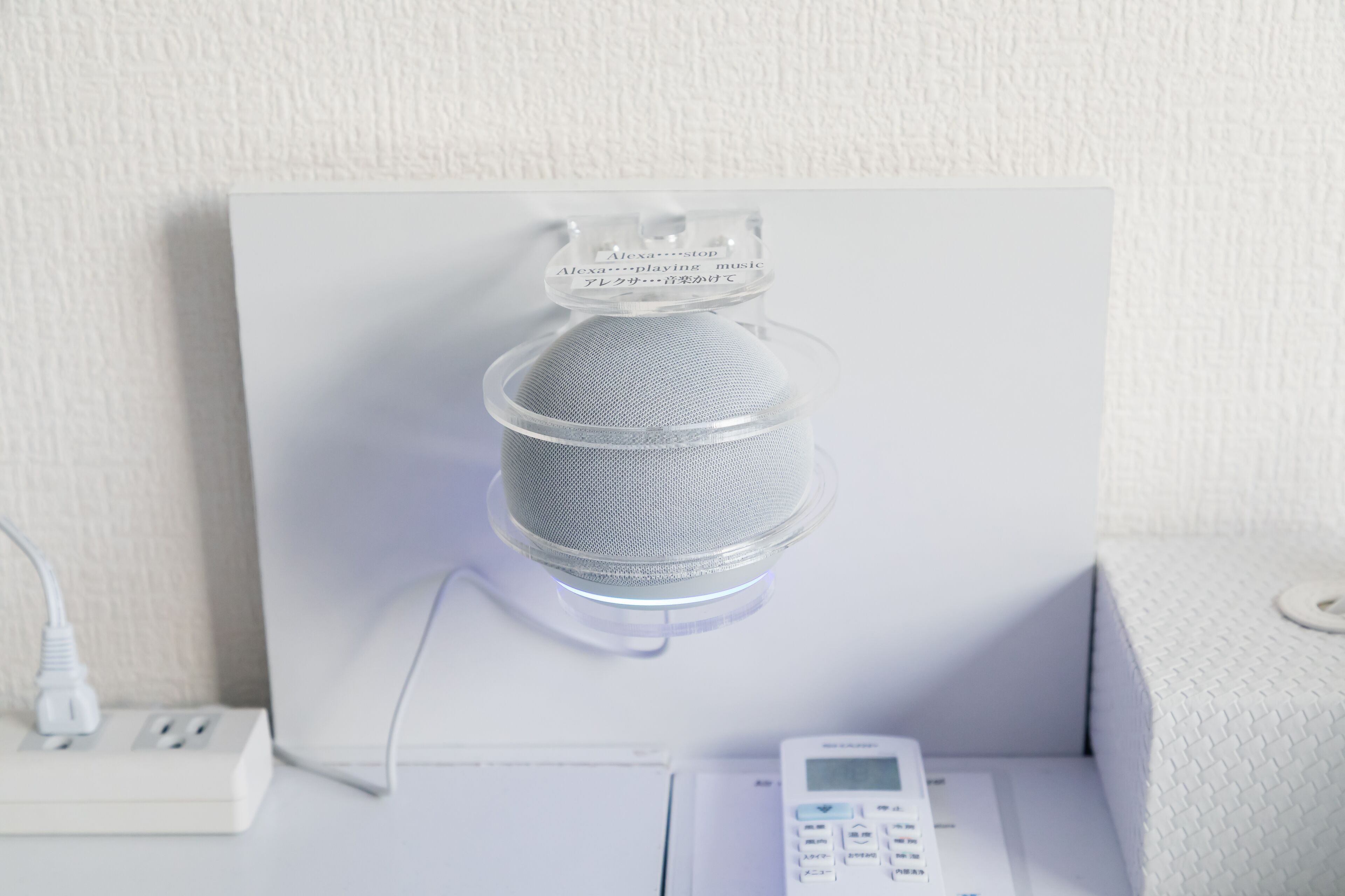 A white power strip with a white device plugged in, a white wall, and a white object with a label.