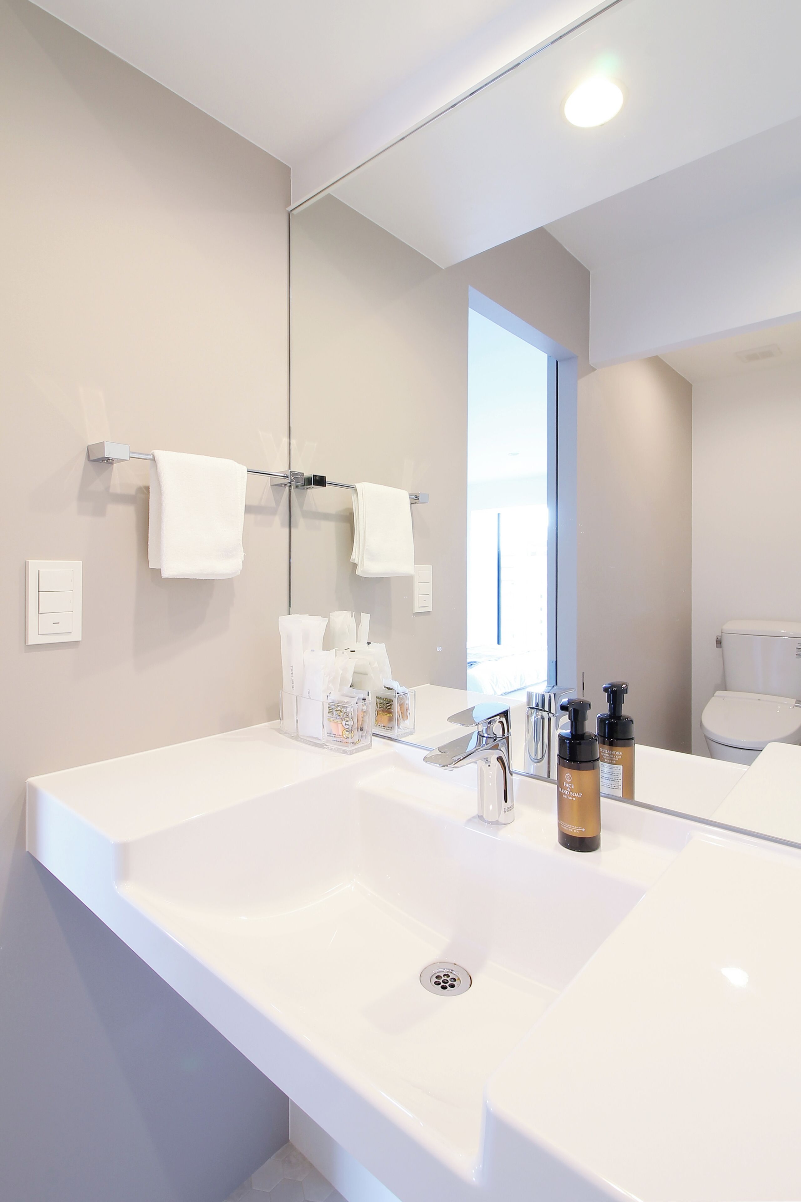 A modern bathroom with a large mirror, two sinks, and a toilet.