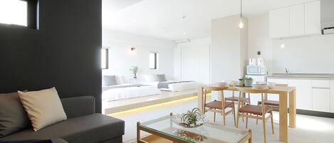 Un salon moderne avec un canapé, une table basse en verre et un coin repas avec des chaises en bois.