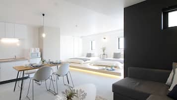 A modern, open-plan living space with a kitchen, dining area, and a cozy seating area with a sofa and a coffee table.