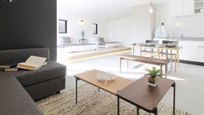 A modern living room with a sofa, a coffee table, and a dining area with a table and chairs.