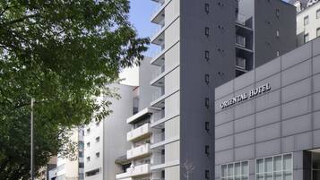 A modern hotel building with balconies and a sign reading "ORIENTAL HOTEL".