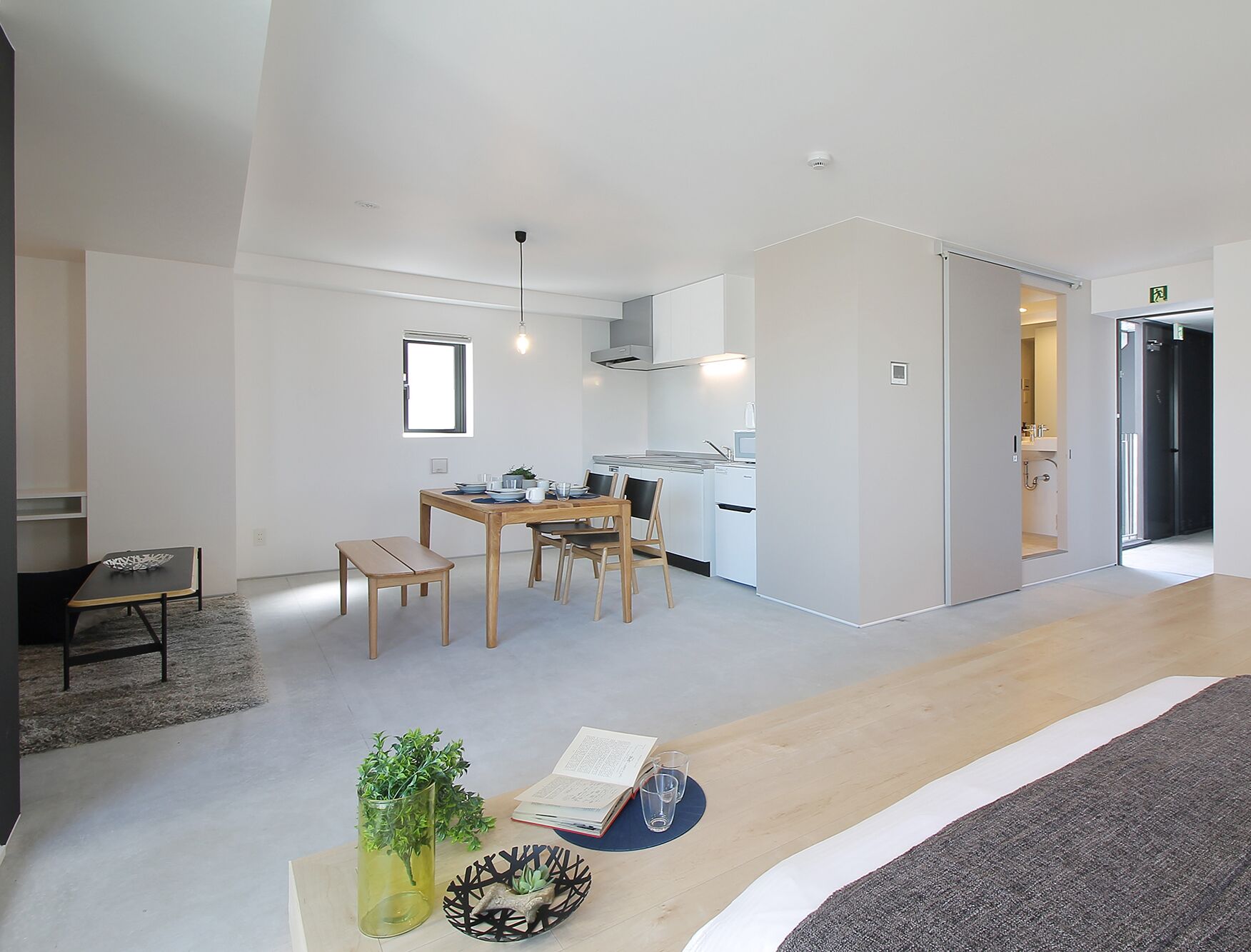 A modern, open-plan living space with a dining area, kitchen, and a separate bathroom.