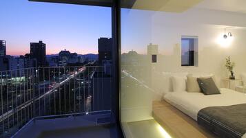 A modern bedroom with a city view, a balcony, and a minimalist design.