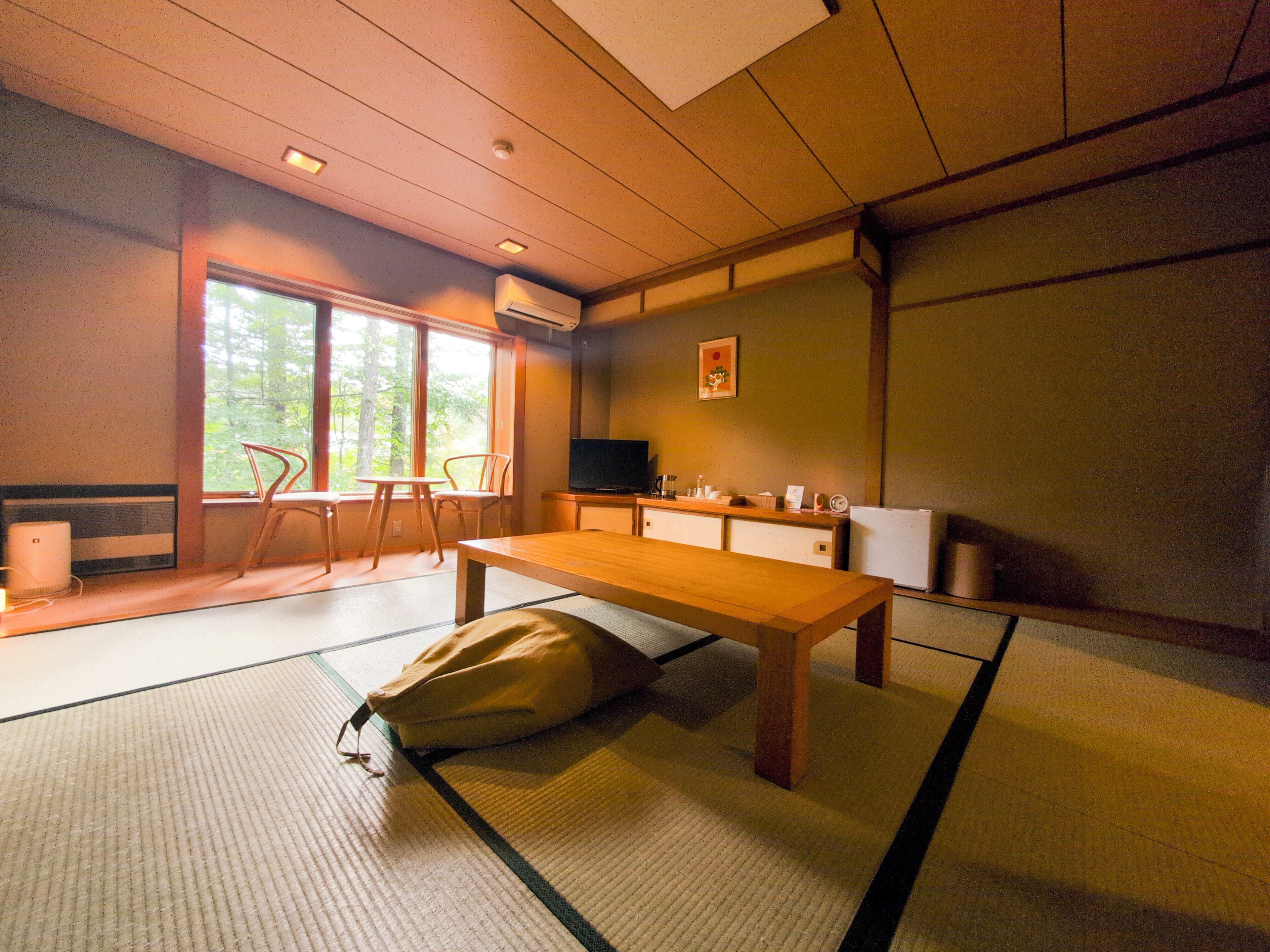 Une pièce de style japonais traditionnel, avec un sol recouvert de tatamis, une table basse, un canapé et un téléviseur.