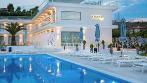 A modern hotel with a swimming pool, outdoor seating, and a well-lit facade. - Laguna Resort (Kassandra)