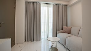 A modern living room with a sofa, a small round table, and a door. - Laguna Resort (Kassandra)