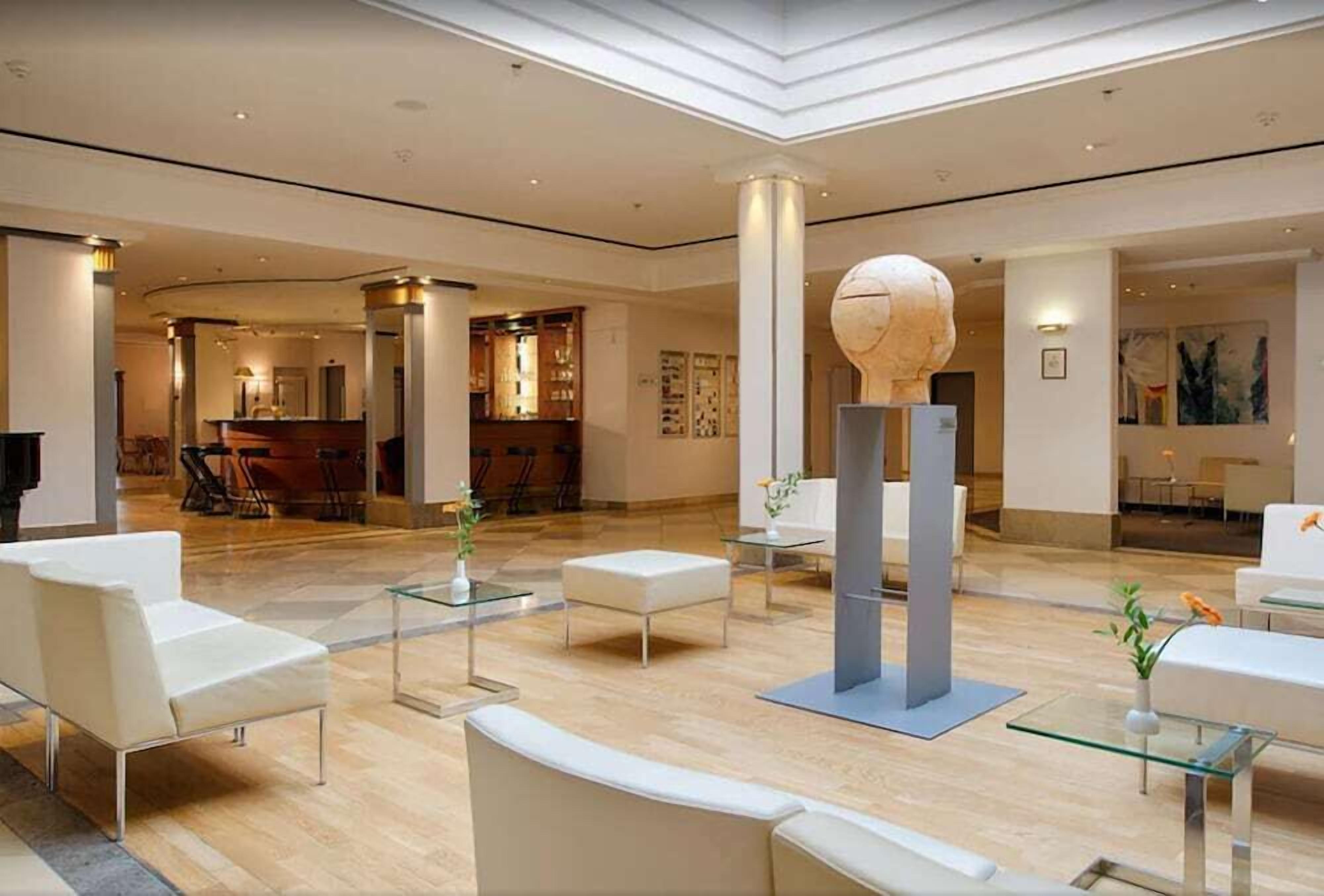 Eine großzügige Lobby mit modernen Möbeln, einer Rezeption und einer einzigartigen, sphärischen Skulptur.