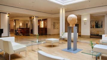 Eine großzügige Lobby mit modernen Möbeln, einer Rezeption und einer einzigartigen, sphärischen Skulptur.
