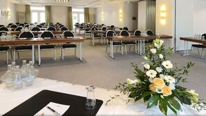 A conference room with multiple tables, chairs, and a floral centerpiece. - Kaiserin Augusta (Weimar)