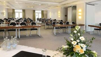 Ein Konferenzraum mit mehreren Tischen, Stühlen und einer floralen Tischdekoration.