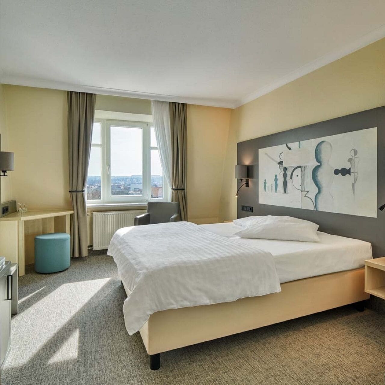 Ein Hotelzimmer mit einem großen Bett, einem Schreibtisch, einem Stuhl und einem Fenster mit Vorhängen.