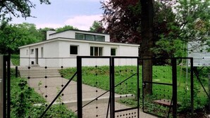 A modern building with a white facade, a gated entrance, and a staircase leading to the entrance. - Kaiserin Augusta (Weimar)
